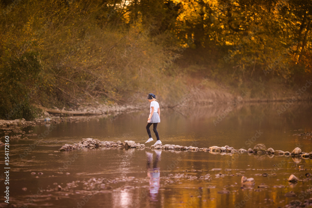 Little blonde girl on the riverside. Autumn in the yellow forest Little blonde girl on the riverside. Autumn in the yellow forest