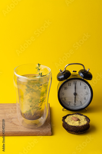 Conceptual food photo of healthy snacks on minimalist bright yellow background: vegan lemon pie and herbal tea