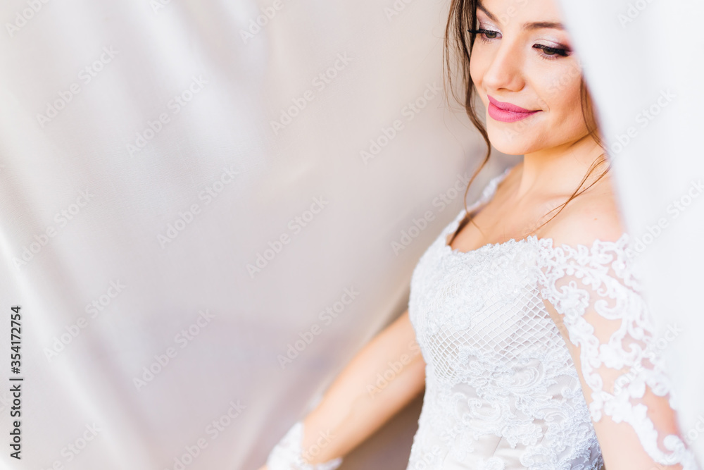 bride in white dress with a beautiful makeup under white curtai bride in white dress with a beautiful makeup under white curtai