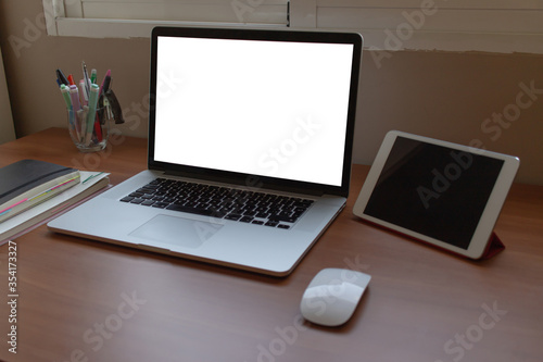 Side shot of computer laptop putting on wooden table with notebook, marker pen, mouse and tablet. Orderly workplace concept.