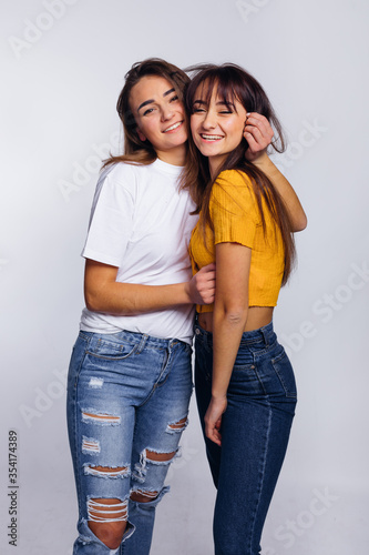 two girls in casual wear hugging and smiling. studio photo.