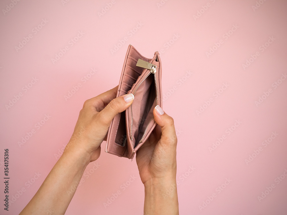 woman hands open empty purse . a pink wallet isolated on pink