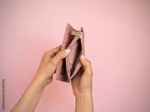 woman hands open empty purse . a pink wallet isolated on pink background