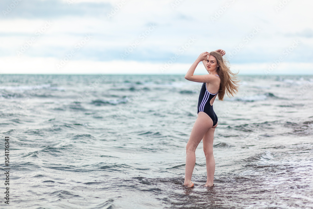 Naklejka premium Beautiful and young blonde girl in a swimsuit relaxing on the sea