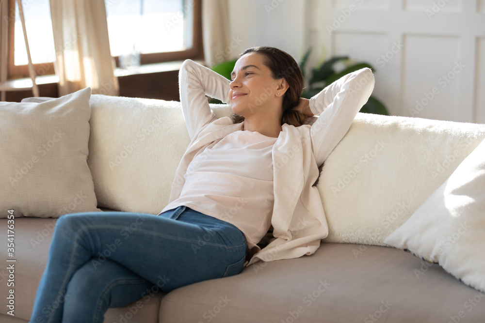 Smiling dreamy millennial Caucasian girl sit relax on comfortable couch in living room look in distance thinking, happy young woman rest on cozy sofa at home on weekend, dreaming or visualizing Smiling dreamy millennial Caucasian girl sit relax on comfortable couch in living room look in distance thinking, happy young woman rest on cozy sofa at home on weekend, dreaming or visualizing