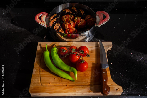 Top view of green peppers,tomatos and knife on wooden cutting board to prepare turkish eggplant kebab, patlican kebab with meatball