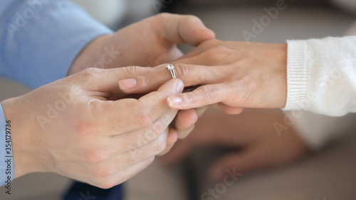 Close up of loving man put beautiful diamond wedding ring propose to beloved woman finger, affectionate male make marriage proposal to girlfriend or female lover, engagement, marry me concept