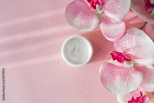 Fototapeta Naklejka Na Ścianę i Meble -  Cosmetic skin face care cream moisturize and orchid flower on pink background. Cosmetology body care lotion
