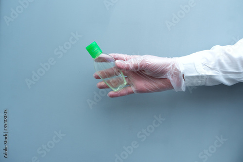 The doctor's gloved hand holds out a bottle of sanitizer. Health protection. Antiseptic.