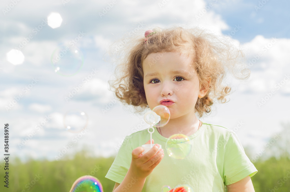 Little beautiful girl blows soap bubbles. Cute baby enjoys outdoor games. happy summer child in nature. Little beautiful girl blows soap bubbles. Cute baby enjoys outdoor games. happy summer child in nature.