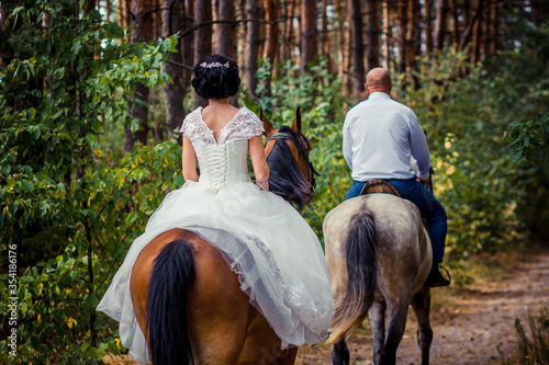 bride and groom riding horses in the forest