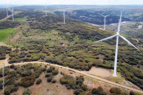 Aerial view of windmills farm for clean energy production on beautiful cloudy sky. Wind power turbines generating clean renewable energy for sustainable development .
