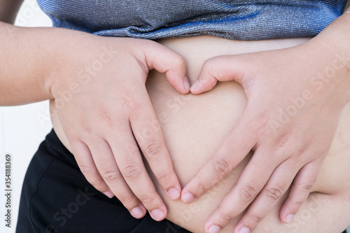 Tablou pe pânză Fat woman shows heart shape hands on stomach for body care, pregnancy diet