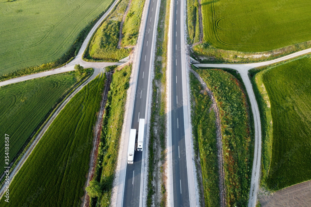 Aerial view of a highway with cars and trucks, in a beautiful countryside scenery .