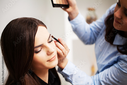 A professional make-up artist makes an evening make-up for a young woman