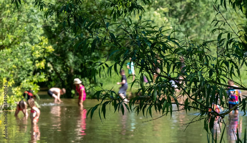 Φωτογραφία Wild swimming: Children (out of focus) swimming in nature, in the River Chess at Chorleywood, Hertfordshire UK