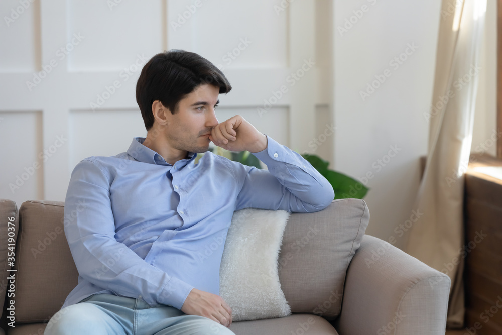 Pensive young caucasian man sit on couch at home look in window distance thinking pondering, thoughtful millennial male lost in thoughts, have relationships or life troubles, make decision Pensive young caucasian man sit on couch at home look in window distance thinking pondering, thoughtful millennial male lost in thoughts, have relationships or life troubles, make decision