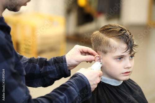 Professional hairdresser cutting childs hair in beauty saloon