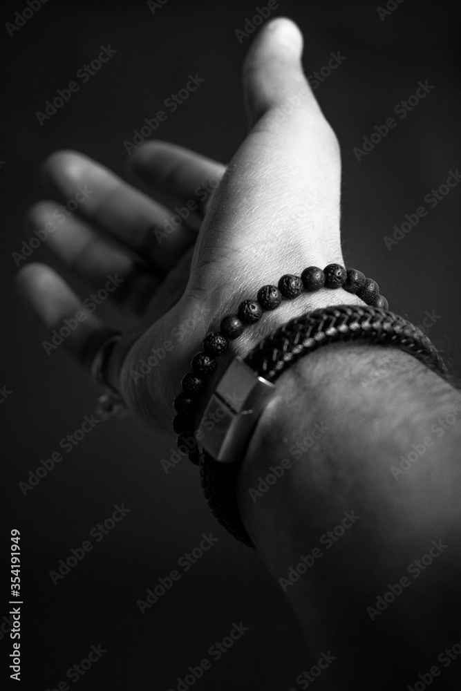 hand wearing bracelets on black background