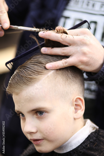 Barber cuts the boy with scissors
