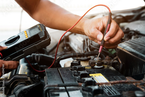 Auto mechanic using measuring equipment tool for fix checking car battery. Concepts of Old car repair service and insurance.