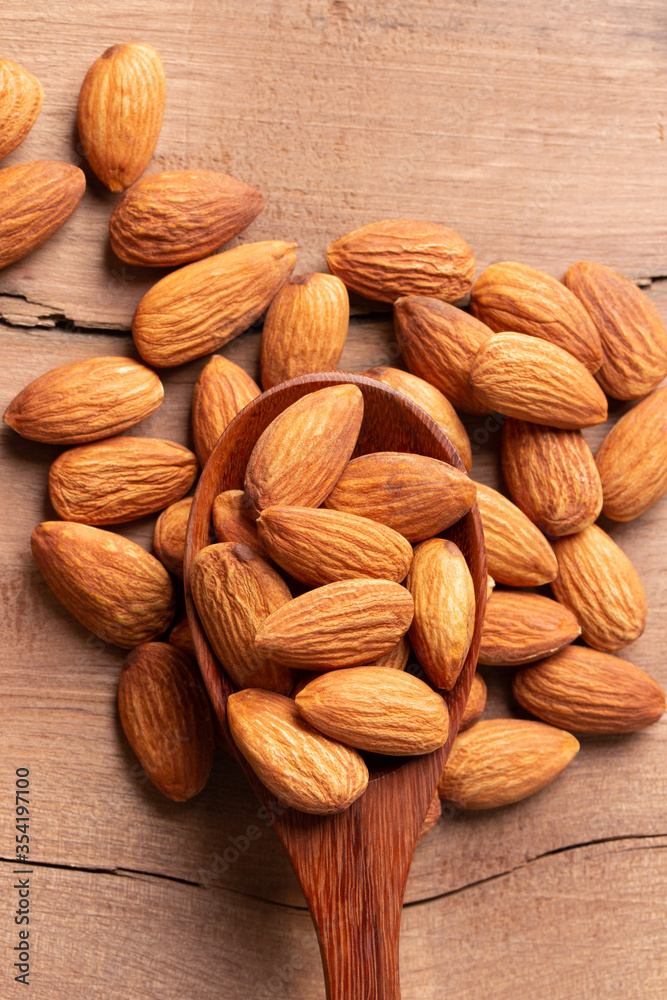 Fototapeta premium Top view peeled almond in wood spoon wood table almond Nuts Ready to use with advertising text