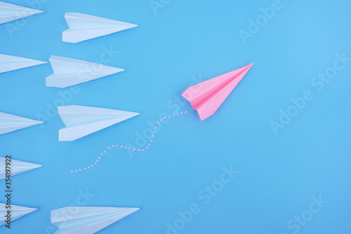 Fototapeta Naklejka Na Ścianę i Meble -  Pink paper plane is different from others on a blue background. Think differently, business leader concept.