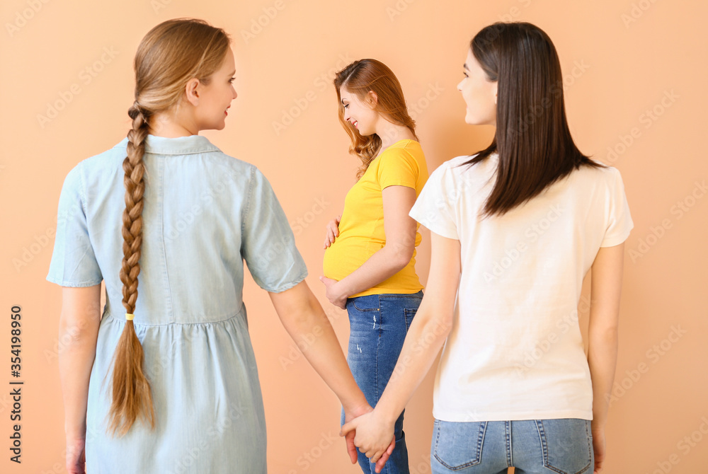 Lesbian couple and pregnant woman on color background. Surrogate motherhood concept Lesbian couple and pregnant woman on color background. Surrogate motherhood concept