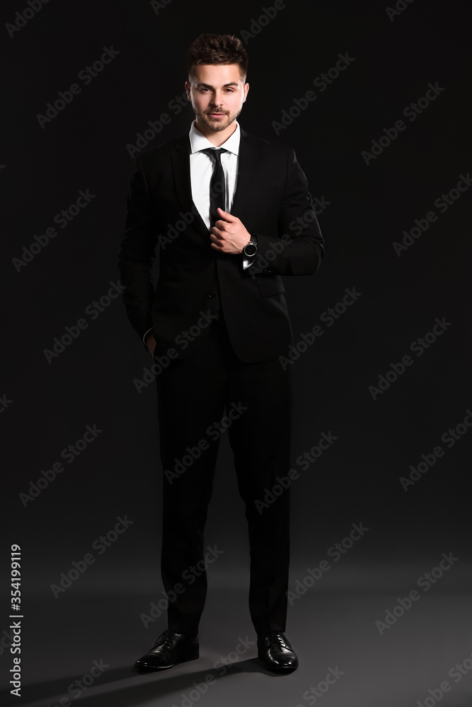 Handsome young man in elegant suit on dark background Handsome young man in elegant suit on dark background