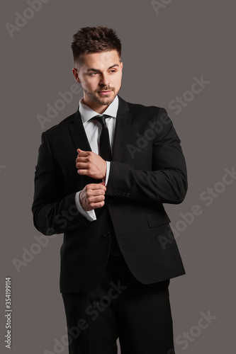 Handsome young man in elegant suit on grey background