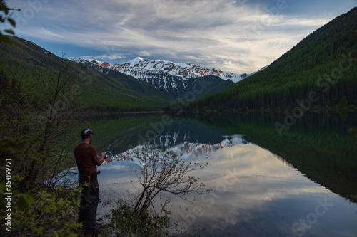 Fisherman at Lake Stanton with reflections of Great Northern Mountain in background