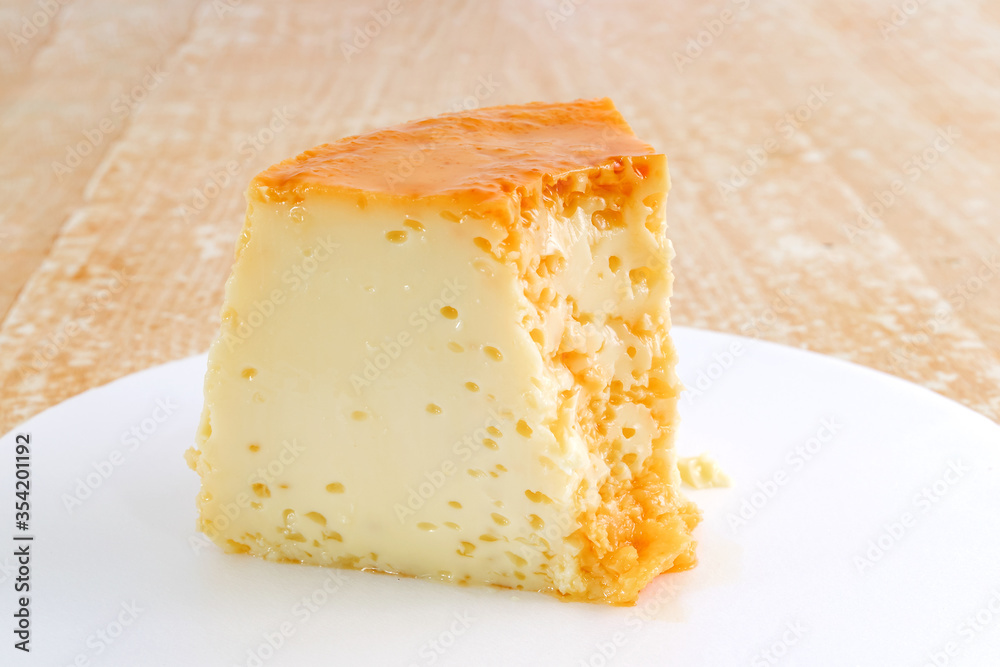 Fatia de pudim de leite condensado com calda de caramelo, tradicional sobremesa brasileira, fotografada isolada em prato branco Fatia de pudim de leite condensado com calda de caramelo, tradicional sobremesa brasileira, fotografada isolada em prato branco