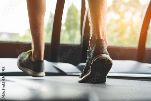 feet of person wearing sportswear walk jogging treadmills in gym.