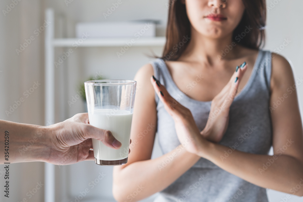 lactose intolerance concept. Woman holding a glass of milk and having a stomachache. lactose intolerance concept. Woman holding a glass of milk and having a stomachache.