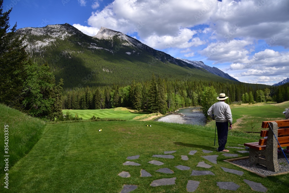 Naklejka premium A man is playing golf in beautiful rocky mountains Banff national park in Alberta, Canada 