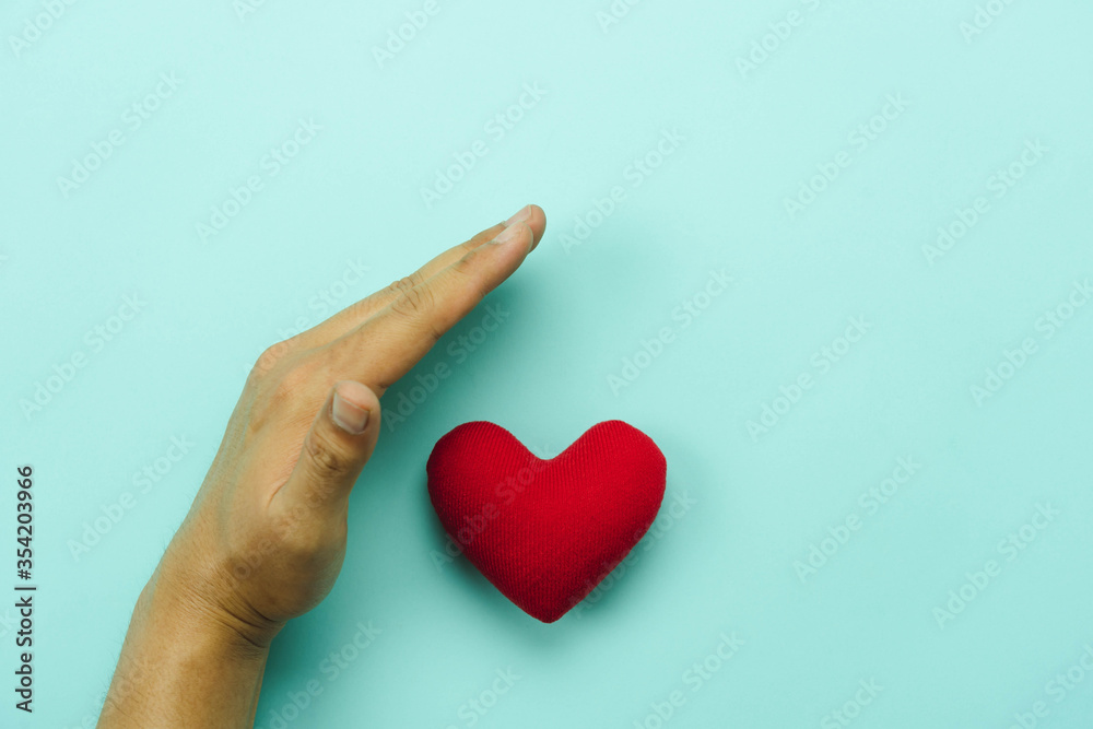 Table top view aerial image of hands protect of red heart on blue paper.Healthcare & medical or valentine background concept. security and insurance, organ donation international day.world health day. Table top view aerial image of hands protect of red heart on blue paper.Healthcare & medical or valentine background concept. security and insurance, organ donation international day.world health day.