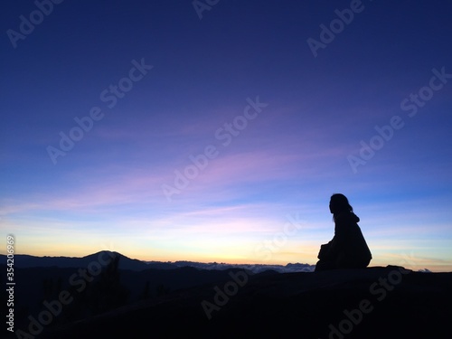 silhouette of a woman sitting on a rock
