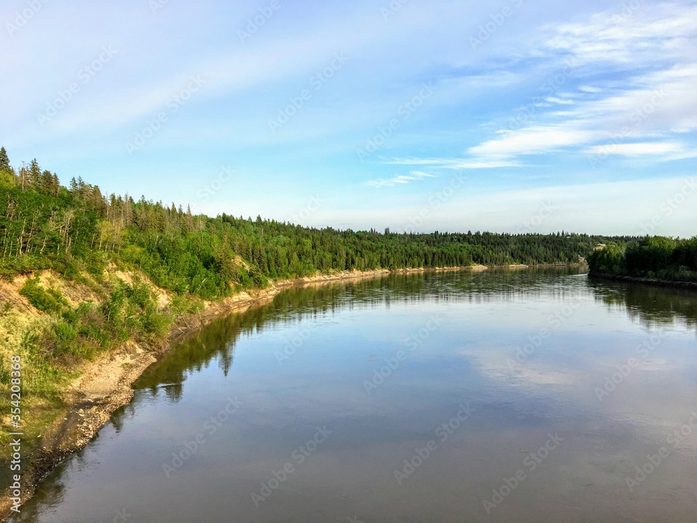 A beautiful photo of a gorgeous blue coloured river surrounded by green forest.  This is the North Saskatchewan River, in Edmonton, Alberta, Canada.