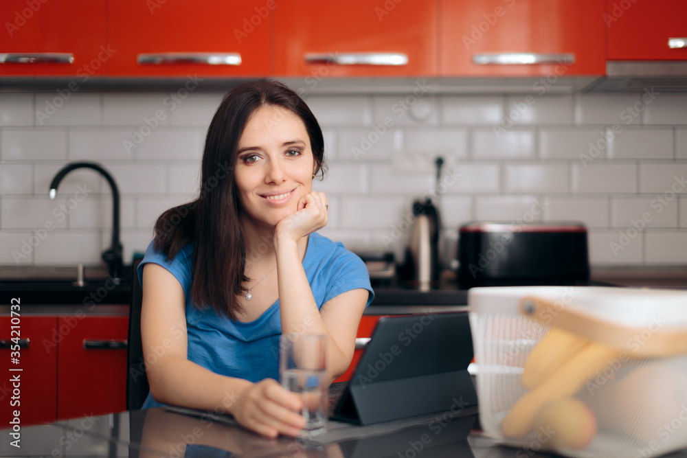 Happy Woman with Pc Tablet Sitting in the Kitchen Happy Woman with Pc Tablet Sitting in the Kitchen