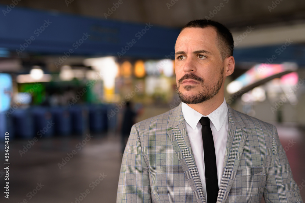 Handsome Hispanic bald bearded businessman walking off at the sky train station