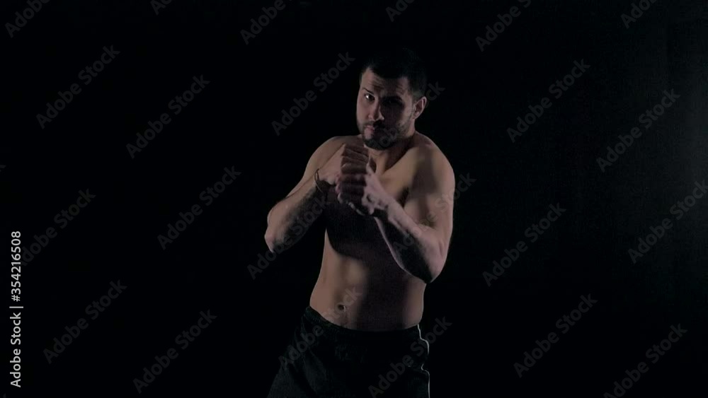Male boxer training on black background. Shadow fight. Silhouette of boxer preparing for big fight. Strength and motivation. Side view. Male boxer training on black background. Shadow fight. Silhouette of boxer preparing for big fight. Strength and motivation. Side view.