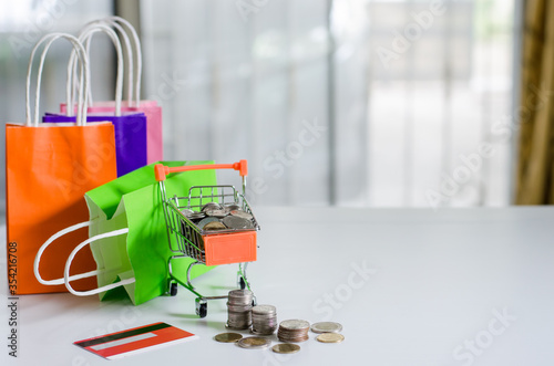 Small cart with paper bag,credit card and coin have on it online shopping located in home concept of detention at home to prevent the Covid19 virus.