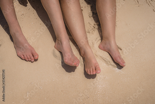 Feet of man and woman on the yellow sand.