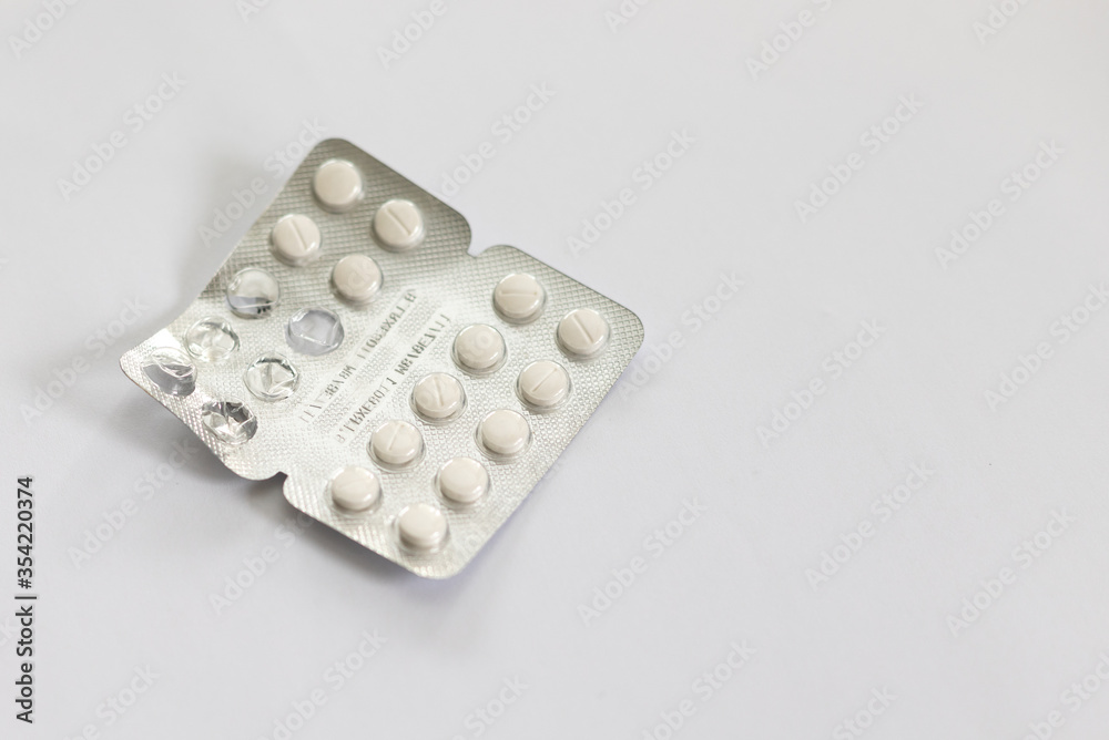 Foil packet of antihistamines with used pills. Small white pills on a white background Foil packet of antihistamines with used pills. Small white pills on a white background