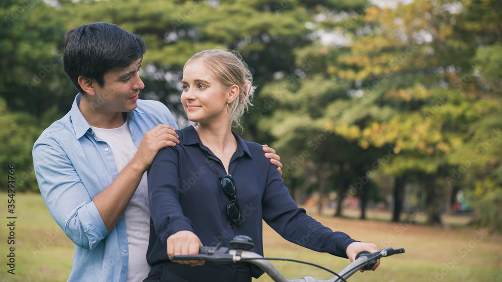 Fototapeta premium young couple riding a bicycle together in the park.