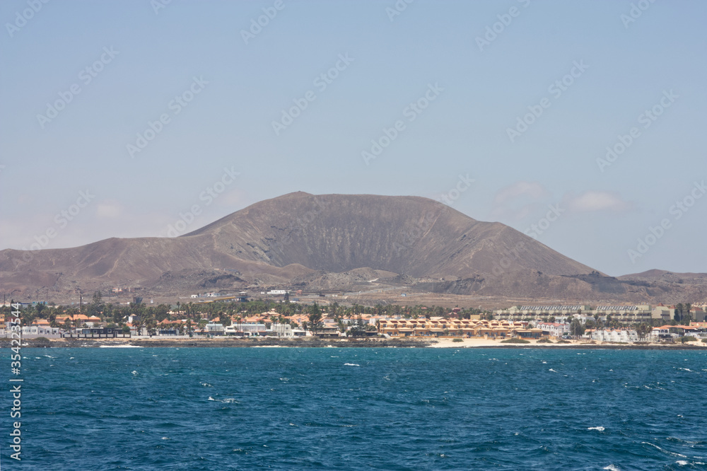 Volcano towering over Corralejo Fuerteventura in the Canary Islands from the sea. Landscape Format Space left for copy.