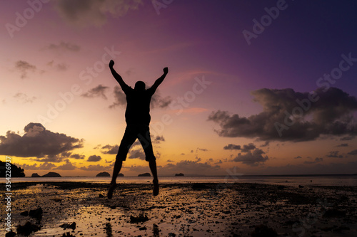 Silhouette of a man on the beach at sunset. Man rejoices meets the sunset