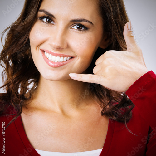 Konstfotografi Studio portrait of happy brunette woman showing call me gesture, over grey backg