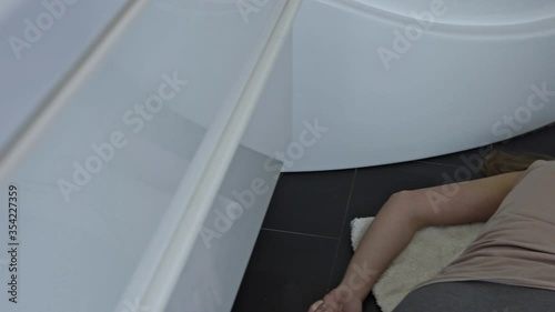 The unconscious woman lies motionless on the floor in the home bathroom.