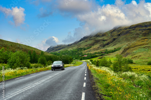 Highway roads and cars in the mountains and valleys in the summer There are wildflowers throughout the countryside in Iceland. Concept for holiday travel driving.